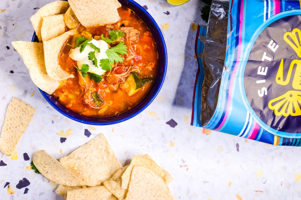 bowl of chicken tortilla soup with bag of tortilla chips