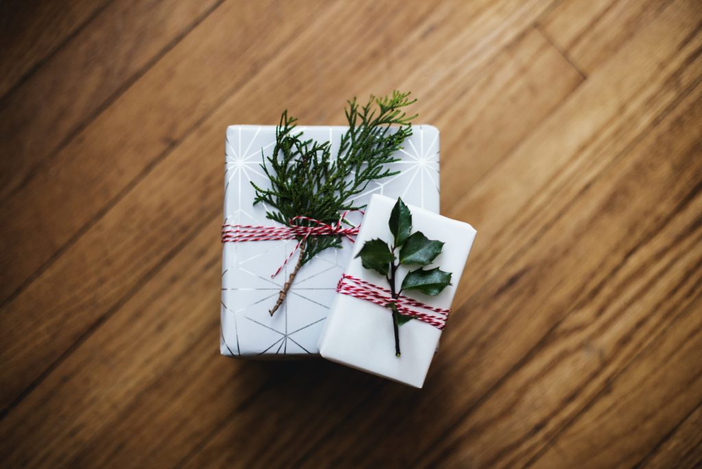 two gifts wrapped in white paper with decorative plants 