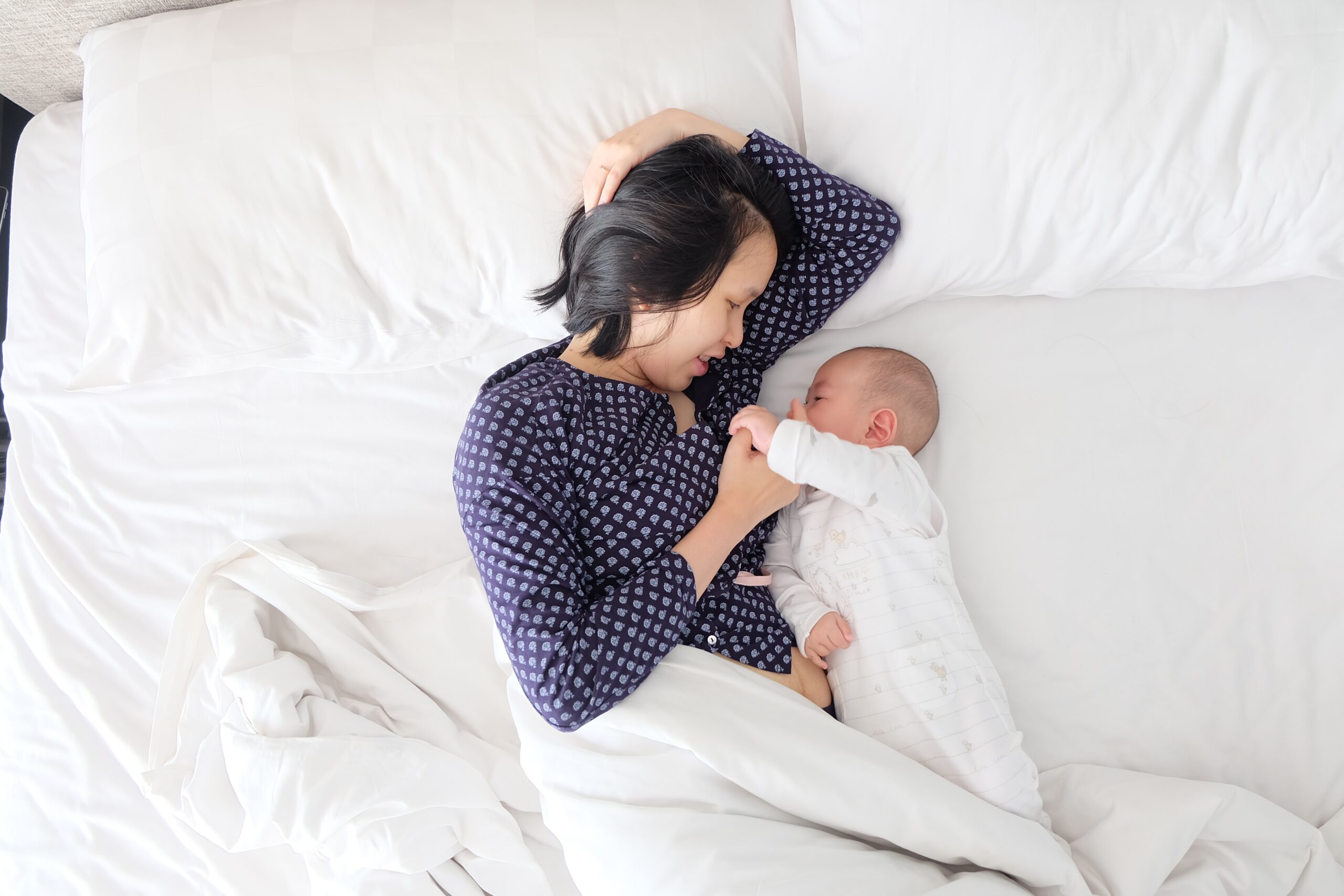 woman laying in bed with young baby next to her